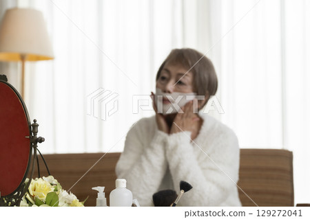 Senior woman taking care of her skin with a face mask 129272041