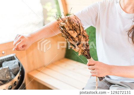 Young Asian woman in sauna wear and t-shirt using vihta in sauna 129272131