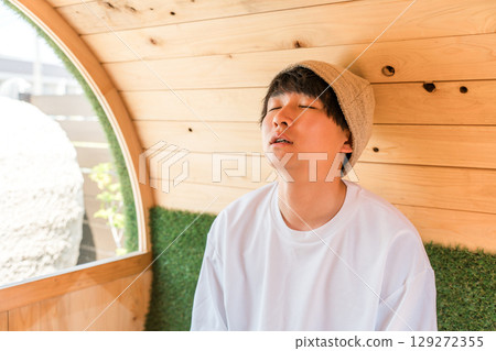年輕的亞洲男子在桑拿房裡戴著桑拿帽 129272355