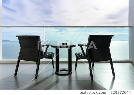 Back view of Two modern rattan armchairs, ashtray on table with sea view under blue sky. view from travel balcony. Summer vacation concept. holiday destination. 129272644