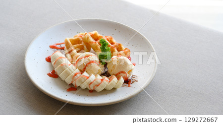 tasty dessert. Croffle serve with ice cream, banana and topping with strawberry syrup. 129272667