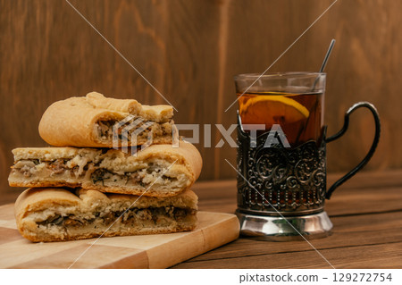freshly baked meat pie with tea served on rustic wooden table. closeup. 129272754