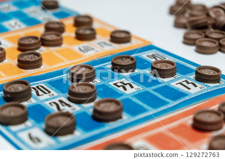 bingo game in progress with colorful cards and brown markers during lively gathering. closeup. 129272763