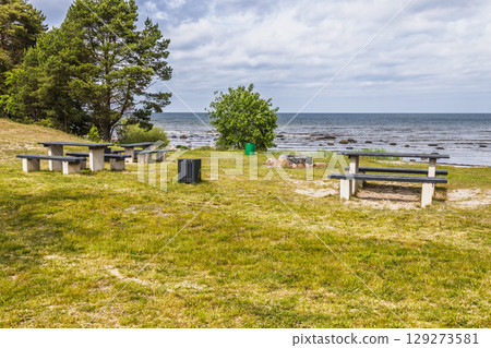 Baltic Sea picnic area with benches, fire pits and waves under cloudy sky Baltic Sea picnic area with benches, fire pits and waves under cloudy sky 129273581