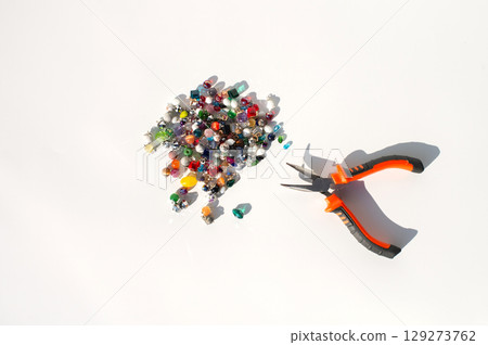 Colorful beads and pliers on white surface - crafting tools and materials Colorful beads and pliers on white surface - crafting tools and materials 129273762