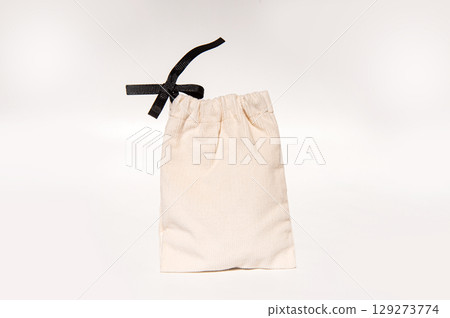 Beige drawstring bag with black ribbon on white background Beige drawstring bag with black ribbon on white background 129273774