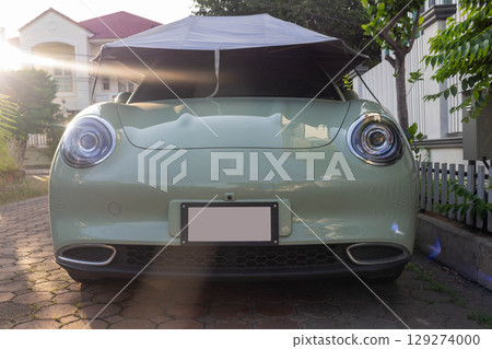 Green Car Parked in Front of House with Roof Covering, Sunlight Shining Green Car Parked in Front of House with Roof Covering, Sunlight Shining 129274000