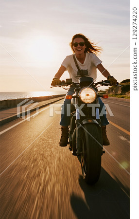 Woman riding a motorcycle along the seaside Woman riding a motorcycle along the seaside 129274220