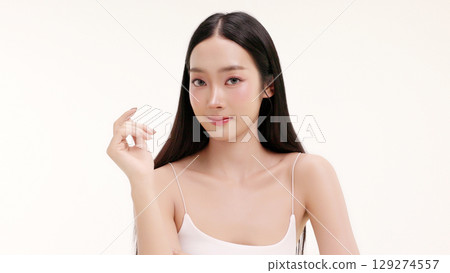 Skincare commercial of featuring a young Asian woman applying natural cosmetic cream in a soft, minimal studio setting. Ideal for promoting beauty, self-care, and organic skincare products. Skincare commercial of featuring a young Asian woman applying natural cosmetic cream in a soft, minimal studio setting. Ideal for promoting beauty, self-care, and organic skincare products. 129274557