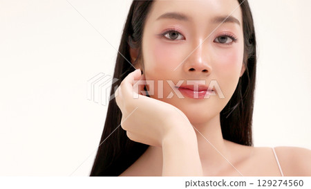 Skincare commercial of featuring a young Asian woman applying natural cosmetic cream in a soft, minimal studio setting. Ideal for promoting beauty, self-care, and organic skincare products. Skincare commercial of featuring a young Asian woman applying natural cosmetic cream in a soft, minimal studio setting. Ideal for promoting beauty, self-care, and organic skincare products. 129274560