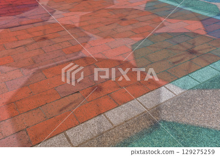 陽光明媚的夏日，地上五顏六色的傘影 129275259