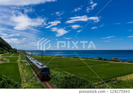 A train running along the coast of the Sea of Japan on a clear day A train running along the coast of the Sea of Japan on a clear day 129275843