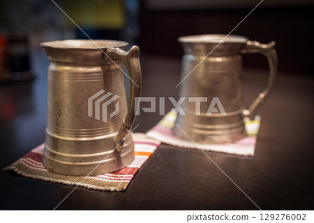 Pair of vintage Japanese beer mugs placed on patterned textile coasters 129276002