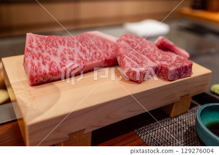 Raw A5 Kobe beef with intense marbling presented on a wooden board at Japanese teppanyaki restaurant Raw A5 Kobe beef with intense marbling presented on a wooden board at Japanese teppanyaki restaurant 129276004