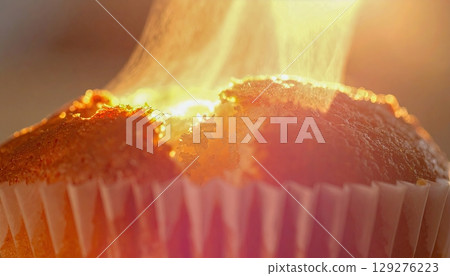 Macro of warm muffin being torn open slowly, rising steam and soft crumbs glowing in morning light, feeling of comfort and care 129276223