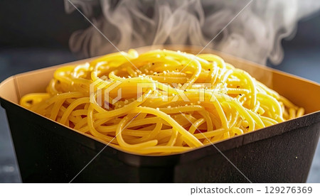 Macro of spaghetti noodles sticking out of a reusable container, steam trails rising in background, focus on glossy sauce details and noodle texture, Warm lunch moment. 129276369