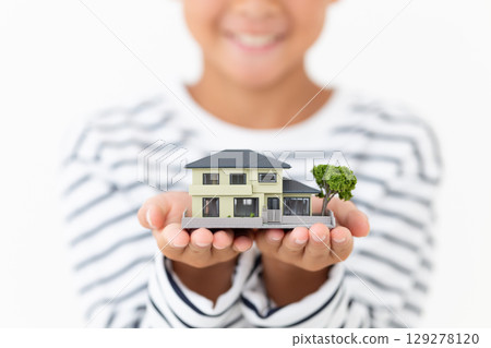 Elementary school boy holding a model of a house Elementary school boy holding a model of a house 129278120