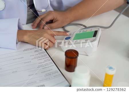 Health Monitoring. Nurse checking blood pressure with a device and medication nearby. Health Monitoring. Nurse checking blood pressure with a device and medication nearby. 129278362