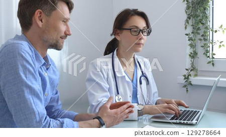 Female doctor consulting with patient in medical office, using laptop to provide healthcare advice and support while discussing treatment options in a professional setting. Medicine concept Female doctor consulting with patient in medical office, using laptop to provide healthcare advice and support while discussing treatment options in a professional setting. Medicine concept 129278664