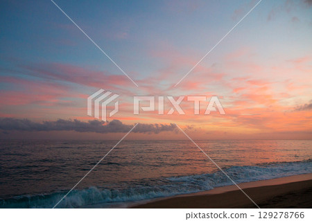 beautiful and colorful sunset, warm light and many clouds, sea waves on the sea coast 129278766