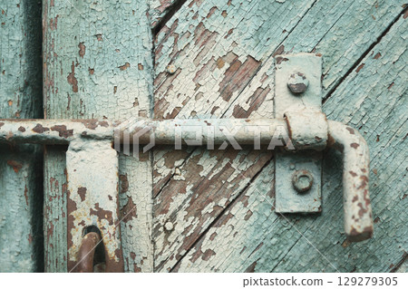 old metal lock on a wooden door with cracked paint 129279305