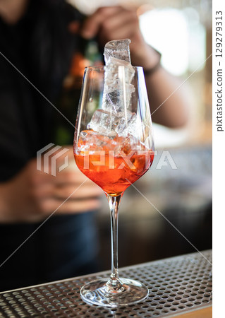 the bartender prepares a beautiful alcoholic cocktail at the bar counter 129279313