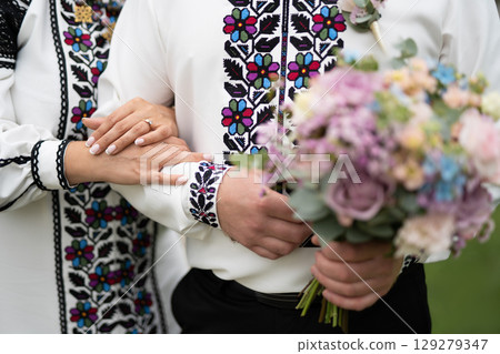 the bride and groom are holding hands with a bouquet of flowers and in traditional Ukrainian clothes the bride and groom are holding hands with a bouquet of flowers and in traditional Ukrainian clothes 129279347