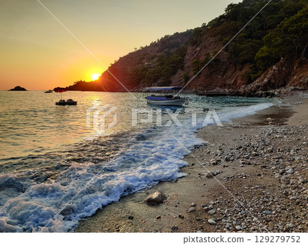 beautiful dramatic landscape of sunset on sea beach with silhouette of boat beautiful dramatic landscape of sunset on sea beach with silhouette of boat 129279752