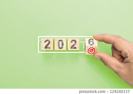 Hand completing 2026 new year business goals. Man putting last wooden block with target icon in white frame concept Hand completing 2026 new year business goals. Man putting last wooden block with target icon in white frame concept 129280157
