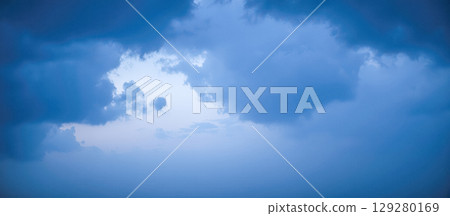 Hole of clear light in dark blue stormy clouds, atmospheric sky background symbolizing hope, freedom, or wonderful new beginning 129280169