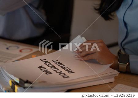 Data Management. Individual reviewing report documents on desk. 129280239