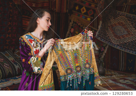 beautiful girl dressed in Turkish national clothes in the room with the interior there are many carpets on the walls 129280653