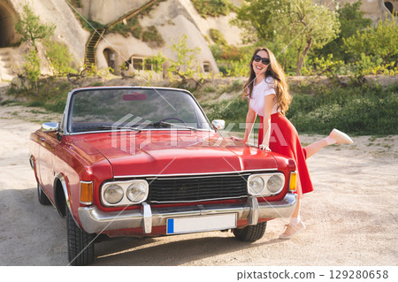 beautiful happy girl in a skirt posing near a retro car in the mountains of cappadocia 129280658