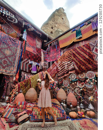 a beautiful girl in dress in a traditional turkish interior with many carpets on the wall 129280730