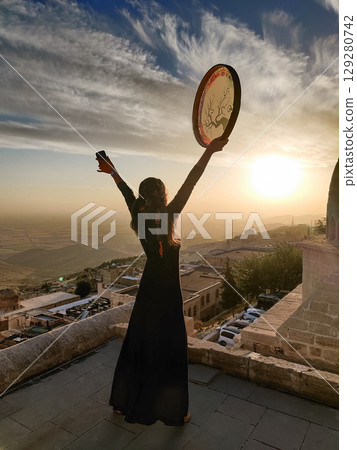 silhouette of a girl with a shamanic drum near Sultan Isa Medrese Mosque in Turkey 129280742