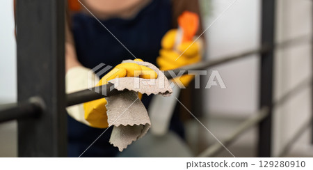 Cleaning Action. Woman scrubbing railing with cloth and spray for a tidy home. 129280910