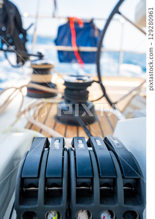 Close-up of rope clutches and winches on the deck of a sailing yacht near Croatia. Sailing equipment, control systems and technical detail of life at sea. Close-up of rope clutches and winches on the deck of a sailing yacht near Croatia. Sailing equipment, control systems and technical detail of life at sea. 129280961