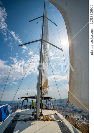White sails filled with wind, seen from the bow of a sailing yacht near Croatia. Freedom, clean energy, adventure and mindful travel on the open sea. White sails filled with wind, seen from the bow of a sailing yacht near Croatia. Freedom, clean energy, adventure and mindful travel on the open sea. 129280965