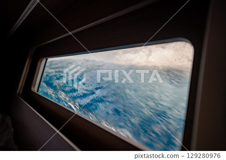 View through the bow cabin window of a sailing yacht leaning into the sea near Croatia. Sailing in strong wind, heeling movement and immersive life on board. 129280976