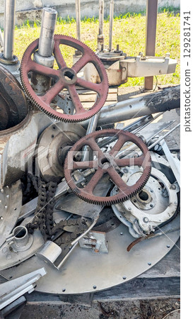 Detailed close-up of various industrial machine parts, featuring gears and chains, highlighting the textures and materials in a mechanical workshop setting Detailed close-up of various industrial machine parts, featuring gears and chains, highlighting the textures and materials in a mechanical workshop setting 129281741