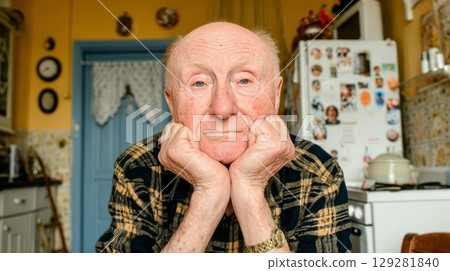 Elderly man with thoughtful expression resting chin on hands, surrounded by cozy kitchen decor, reflecting on memories and life experiences Elderly man with thoughtful expression resting chin on hands, surrounded by cozy kitchen decor, reflecting on memories and life experiences 129281840