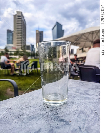 Urban scene with clear glass on foreground table, skyscrapers and crowd blurred behind. High quality photo 129282054