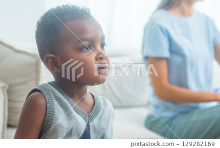 young boy is sitting on  couch with his eyes closed 129282169