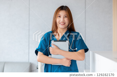 woman in blue scrubs is holding tablet in her hand woman in blue scrubs is holding tablet in her hand 129282170