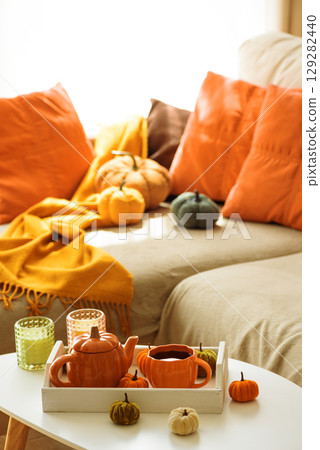 Autumnal living room decor with pumpkins, a teapot, tea cup, and cozy blankets. 129282440