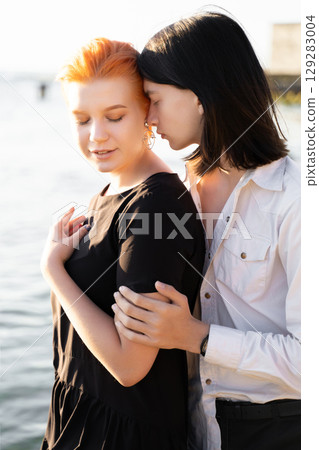 two lovers boy and girl are happy walking and hugging on the sandy beach near the sea. 129283004
