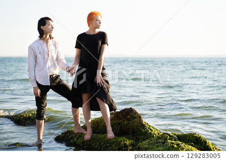 two lovers boy and girl are happy walking and hugging on the sandy beach near the sea. 129283005