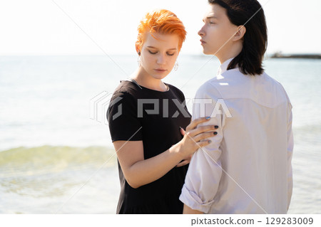 two lovers boy and girl are happy walking and hugging on the sandy beach near the sea. 129283009