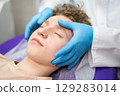 a cosmetologist doctor makes cosmetic procedures on the face of a young guy in a beauty salon 129283014