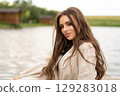 beautiful girl with long hair posing outdoors on the lake shore. 129283018